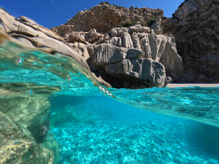 Underwater split photo of famous paradise turquoise pebble beach of Seychelles in island of Ikaria,...