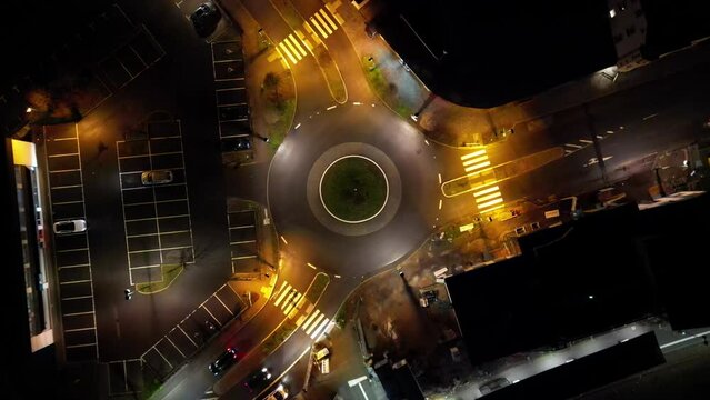 Topshot: Kreisverkehr in einer deutschen Kleinstadt bei Nacht. Fahrende Autos auf den Stra&szlig;en der Stadt. Ruhiger Verkehr. Fu&szlig;g&auml;nger&uuml;berwege. Drehende Kamera. Aufsicht von oben.