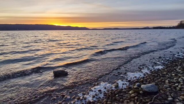 Sonnenuntergang am sch&ouml;nen Bodensee mit Wellen und bunten Wolken am Himmel 