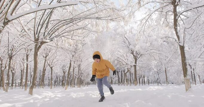 Happy kids playing with snow in a beautiful park on a sunny winter day, boy and girl running outdoors in cold winter, winter holidays, 4k slowmotion