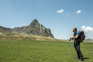 Hiker man spotting a peak from a meadow