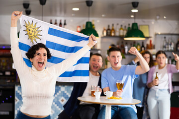 Fans with the flag of Uruguay celebrate the victory of their favorite team in a beer bar