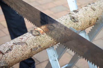 Details eines Sägebock mit Baumstamm und Säge bei einer Hochzeit.
