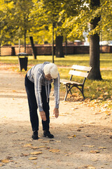 Senior grey-haired woman stretching in the park . High quality photo