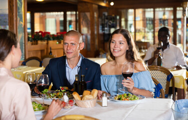 Two cheerful couples having dinner and nice talking in restaurant