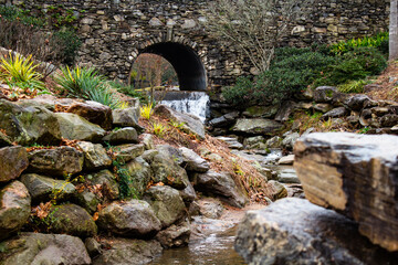A small waterfall with a stream next to a stone wall