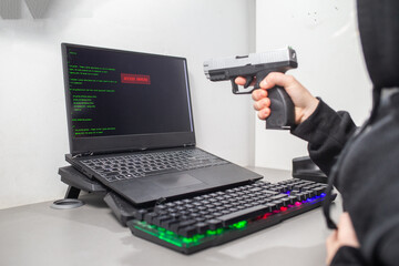 Człowiek celujący z broni do laptopa. Laptop wyświetlający napis ACCESS DENIED. Laptop wyświetlający komunikat BRAK DOSTĘPU. Hacker celuje z broni. Celowanie z pistoletu. Hacker aims with a gun. - obrazy, fototapety, plakaty