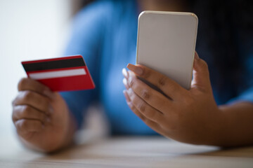 Cropped of dark-skinned chubby woman holding phone and bank card