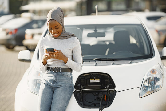 African American girl charging electro car at the electric gas station