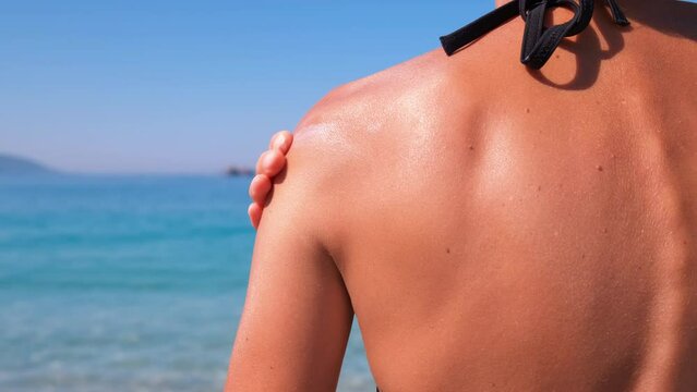 Use sunscreen lotion on resort. A tourist woman apply sunscreen lotion on her skin on the beach. A concept of sun spf protection during traveling under sun.