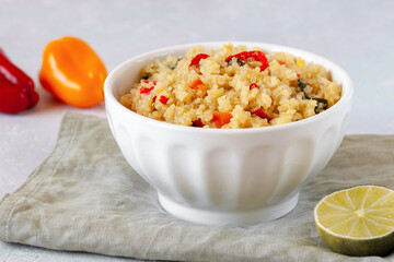 Bowl of quinoa cooked with red and yellow bell pepper and spinach