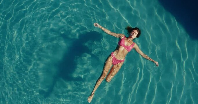 Aerial view of beautiful woman floating and relaxing in the the pool at luxury resort spa