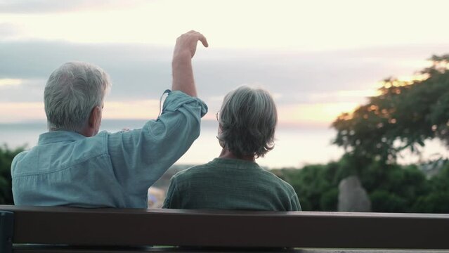 Head shot close up portrait happy grey haired middle aged woman with older husband, enjoying sitting on bench at park. Bonding loving old family couple embracing, looking sunset.