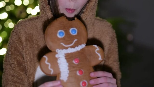 kid eating a gingerbread man in hands and has a fun on christmas decoration background