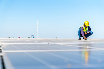 African man engineer using digital tablet maintaining solar cell panels on building rooftop. Technician working outdoor on ecological solar farm construction. Renewable clean energy industry concept.