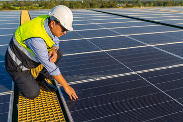 Asian man engineer using digital tablet maintaining solar cell panels on building rooftop....