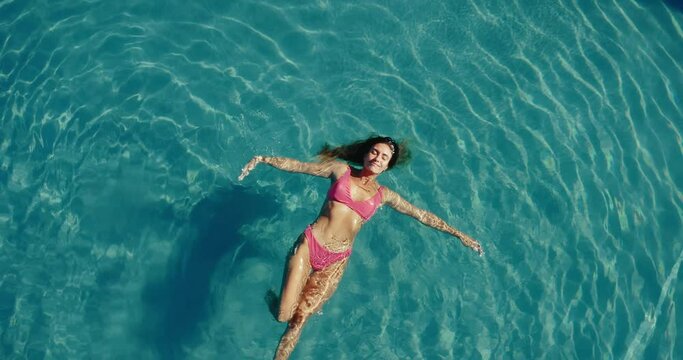 Aerial view of beautiful woman floating and relaxing in the the pool at luxury resort spa