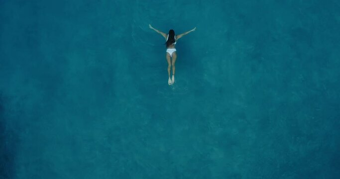 Aerial view of beautiful woman swimming in the the pool at luxury resort spa at sunrise