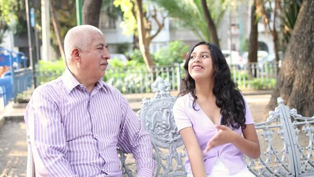 Grandfather and granddaughter talking in the park.