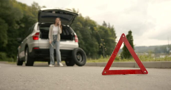 Red triangle sign behind the woman near broken car