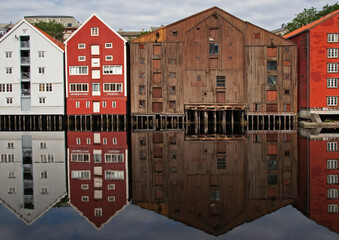 panoramic view of old colorful wooden houses with reflections in river Nidelva in the Brygge district in Trondheim, Norway