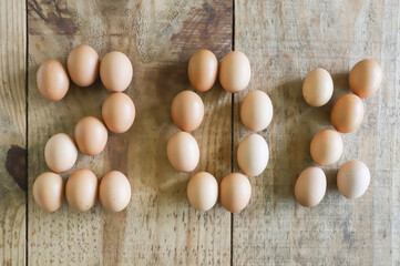 20% numeral written with chicken eggs, arranged on a pine wood table.