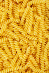 Raw dry fusilli pasta, food background texture, top view