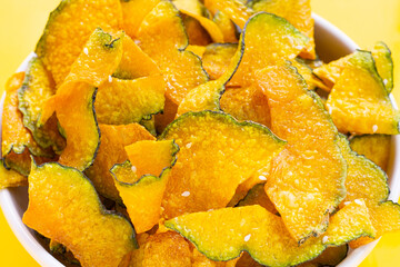 Green pumpkin slice chips on yellow background.