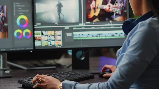 Young content creator editing video and audio montage on computers, creaating movie with professional studio footage. Female videographer using color grading to edit clips in post production agency.
