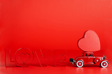 red retro car delivers a red heart on a red background. The word LOVE is written in red letters....