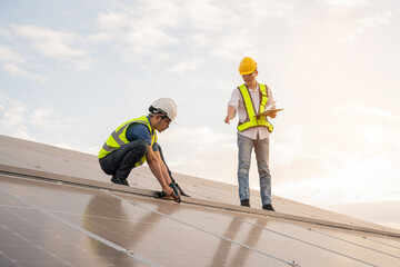 Engineering team working on checking and maintenance in solar power plant, Solar panel technician with drill installing solar panels on roof on a sunny day