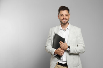 Happy teacher with stationery against beige background