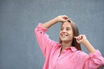 Beautiful young woman in stylish shirt near grey wall, space for text