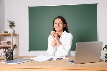 Young teacher giving lesson at table in classroom