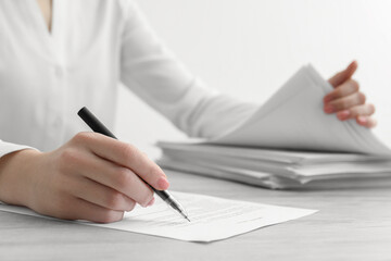Woman signing documents at wooden table in office, closeup. Space for text