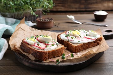 Delicious sandwiches with radish, egg, cream cheese and microgreens on wooden table