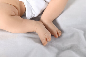 Little baby in bodysuit on bed, closeup