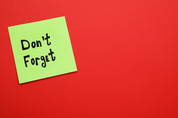 Paper note with phrase Don't Forget on red background, top view. Space for text