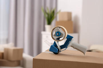 Dispenser with roll of adhesive tape on box indoors. Space for text