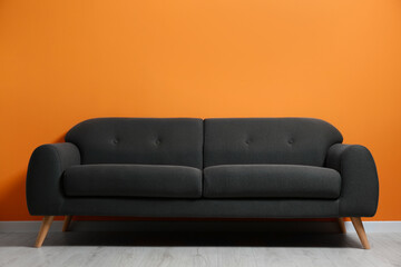 Stylish room with cosy sofa near orange wall. Interior design