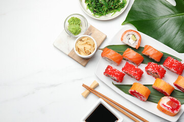 Flat lay composition with delicious sushi rolls on white marble table. Space for text