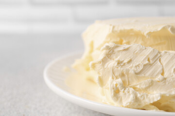 Plate with tasty homemade butter on white textured table, closeup. Space for text