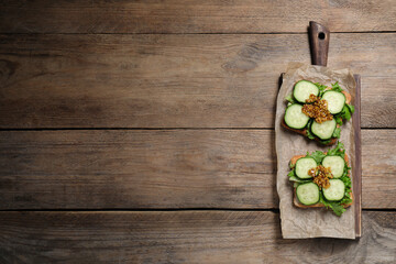 Tasty cucumber sandwiches with arugula and mustard on wooden table, top view. Space for text