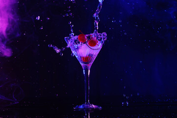 Pouring fresh martini into glass on table in neon lights