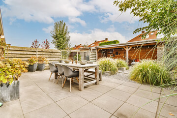 an outdoor patio with table, chairs and potted plants in the background is a blue sky filled with...