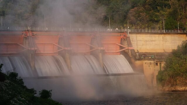 Hydroelectric dam, floodgate with flowing water through gate and open springway at Kew Lom Dam, Lampang, Thailand. Dam