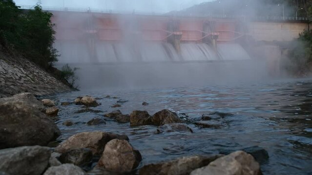 Hydroelectric dam, floodgate with flowing water through gate and open springway at Kew Lom Dam, Lampang, Thailand. Dam