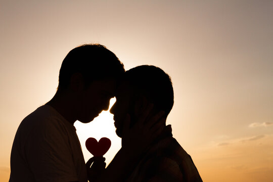 Pareja homosexual mirandose en un atardecer romantico. 