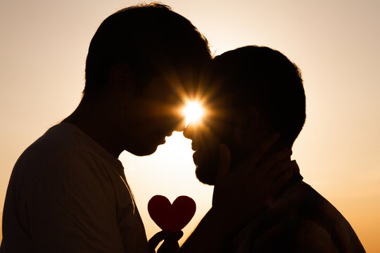 Pareja homosexual mirandose en un atardecer romantico. 