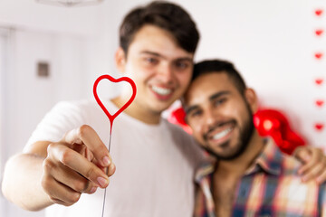 Tierna pareja homosexual sonriendo con un corazon por San Valentin 